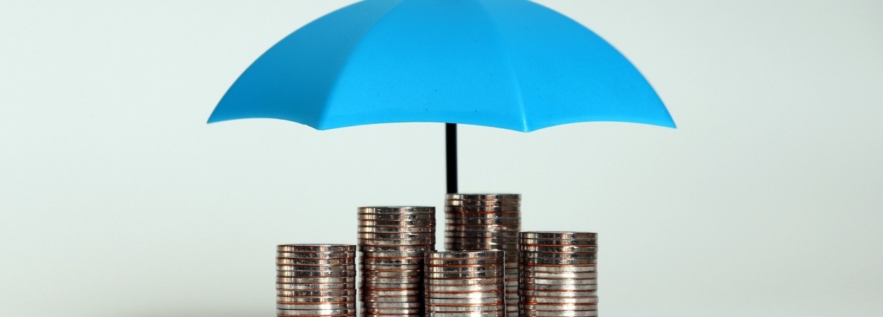 Een stapel van munten met een open blauwe paraplu.